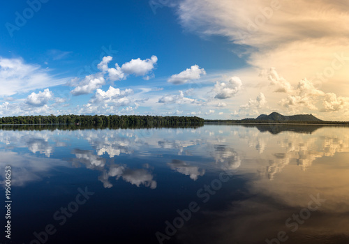 Fototapeta Naklejka Na Ścianę i Meble -  View of Negro River with rainforest and hill in the background and clouds reflected in water at dusk