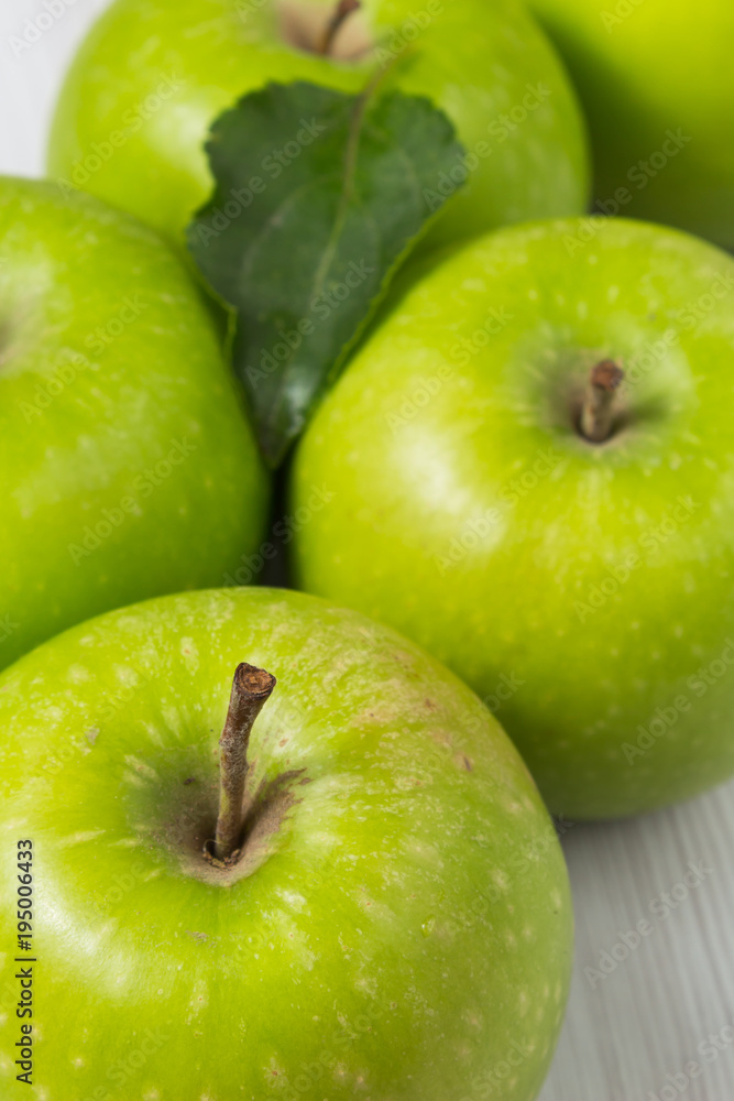 Green apples with leaves on white wooden table Vertical composition Green apples with leaves on white wooden table Vertical composition