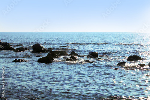 Wallpaper Mural Big stones in the sea. Big stones not far from the beach form breakwaters. Small waves reflect the blue sky in different nuances. Torontodigital.ca