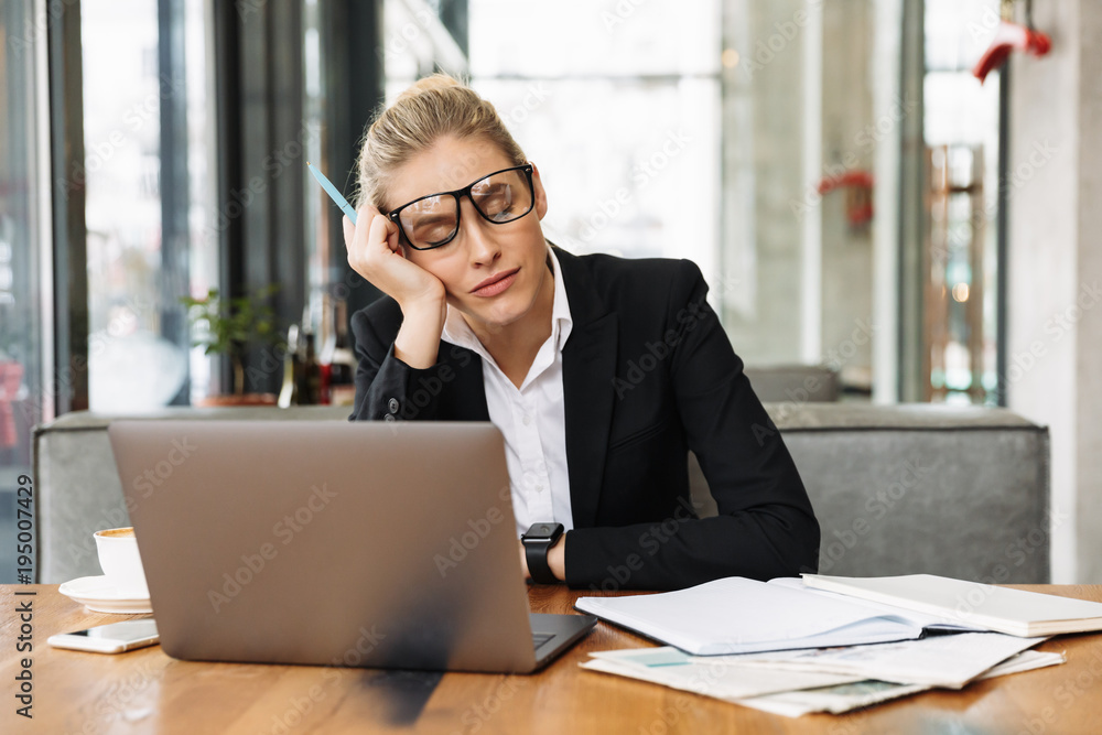 Fototapeta premium Tired blonde business woman sitting by the table in cafe