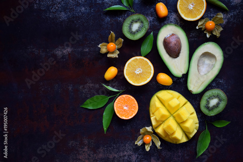 Fototapeta Naklejka Na Ścianę i Meble -  Mix of ripe tropical fruits with avocado mango, kumquat, kiwi, citrus. Superfood background. Vegetarian raw food. Copy space