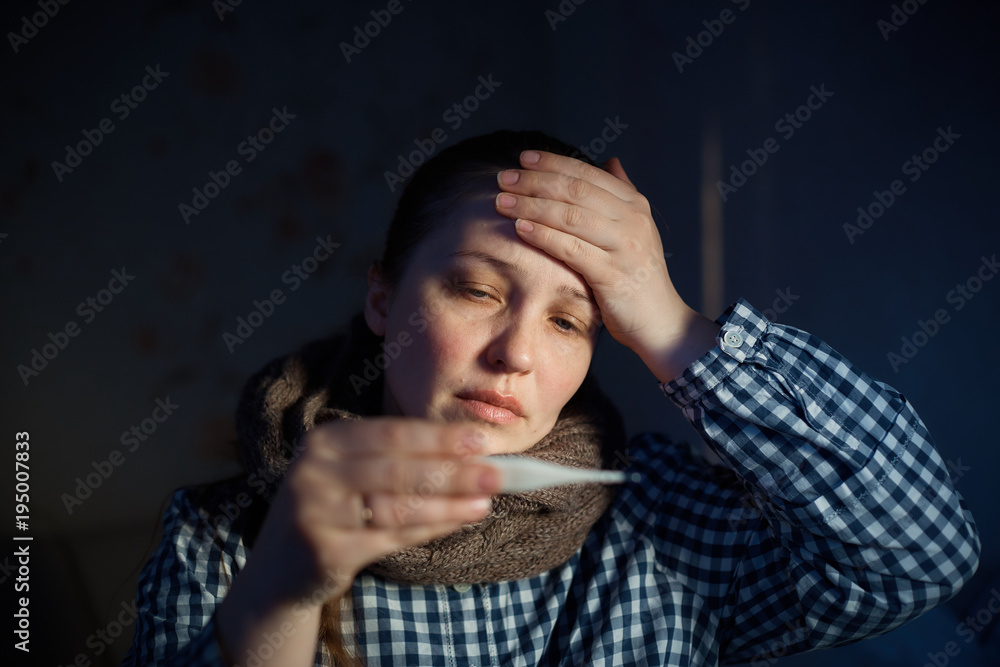 a young woman measures the temperature with an electronic thermometer. Colds, malaise, health problems a young woman measures the temperature with an electronic thermometer. Colds, malaise, health problems