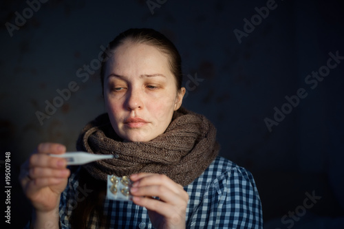 a young woman measures the temperature with an electronic thermometer. Colds, malaise, health problems