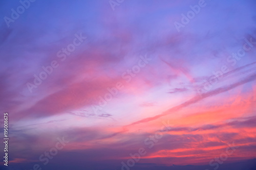 Dark blue sky with red coral streaks shining throughout clouds. Cloud art. Dark tone picture