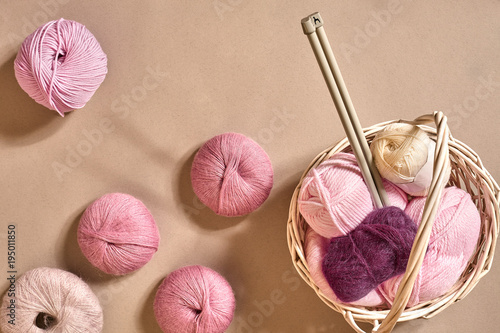 Yarn balls. Balls of colored yarn in a wicker dish. Yarn for knitting on a beige background. Knitting as a kind of needlework. Knitting needles and multi-colored yarn look bright. photo