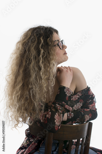 Woman with curly hair and floral dress posing on white background