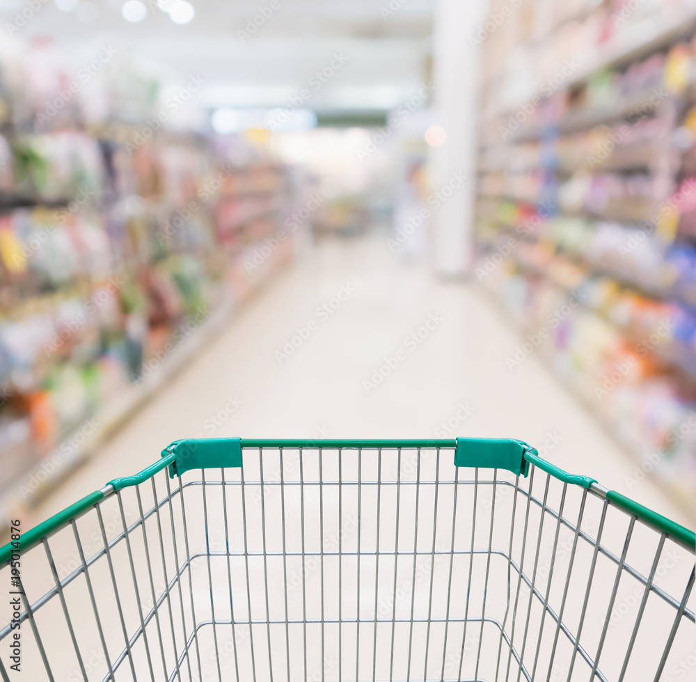 Empty shopping cart with abstract blur supermarket discount store aisle and product shelves interior defocused background