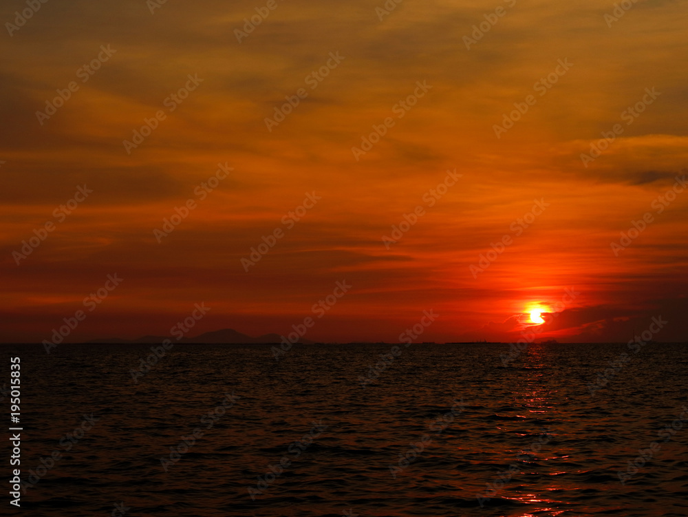 sunset last on horizontal in right frame over orange sky and ocean