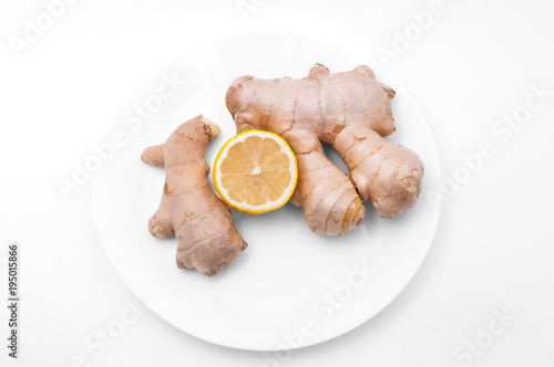 On a white background a plate of ginger and a half of fresh lemon.