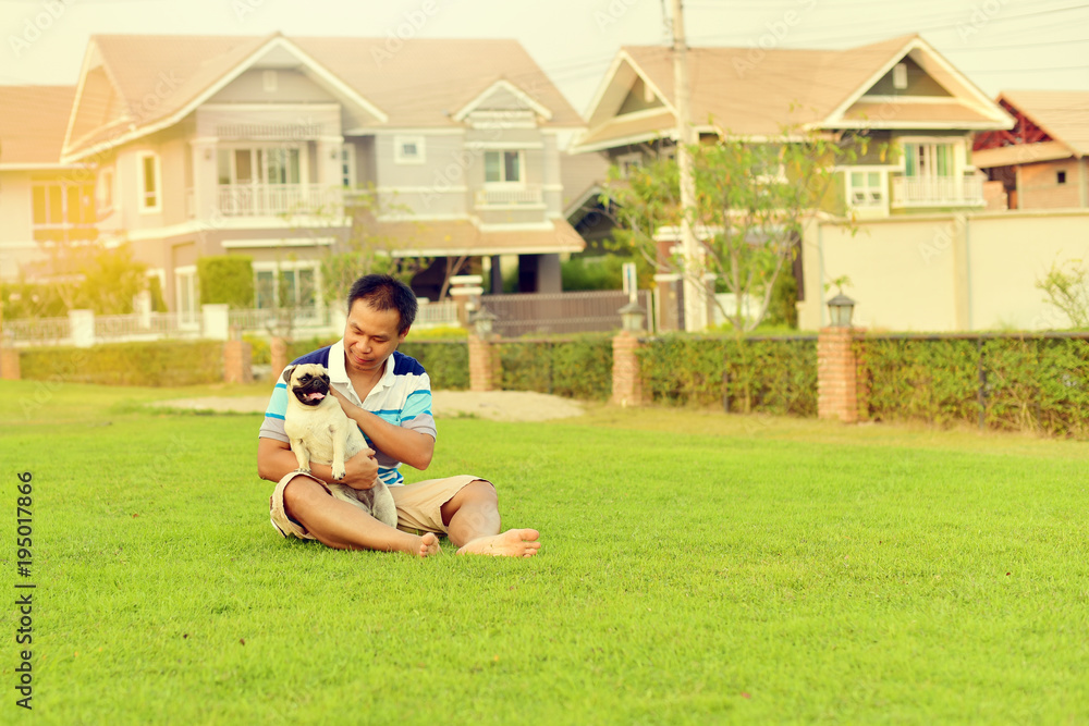 Happy Asian man playing with his dog in garden
