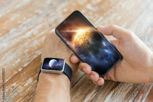 close up of hands with smartphone and smart watch