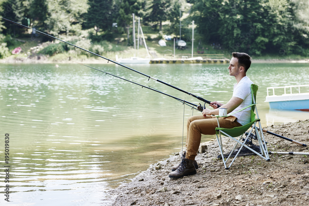 Men with fishing rod sitting on fishing chair Men with fishing rod sitting on fishing chair