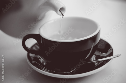 Green tea being poured into a cup from a kettle (black white image)