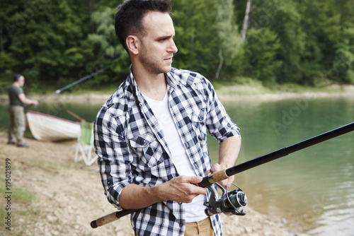 Serious men catching fish by a lake