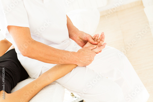 Fisioterapeuta haciendo masajes en los brazos de una joven mujer. Vista superior y de cerca