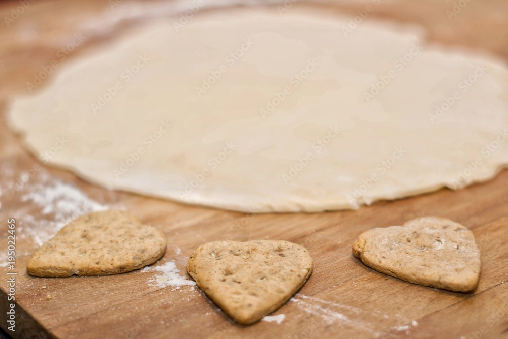 Heart shaped cookies and dough on a wooden board.Selective focus. Heart shaped cookies and dough on a wooden board.Selective focus.