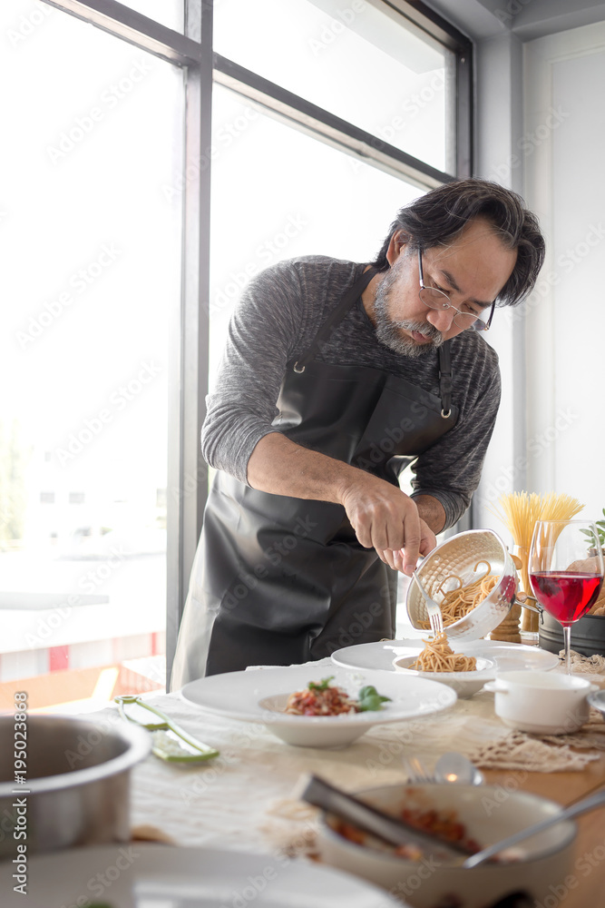 Handsome bearded cheef cook prepairing spaghetti on a kitchen, Chef cooks meal Handsome bearded cheef cook prepairing spaghetti on a kitchen, Chef cooks meal