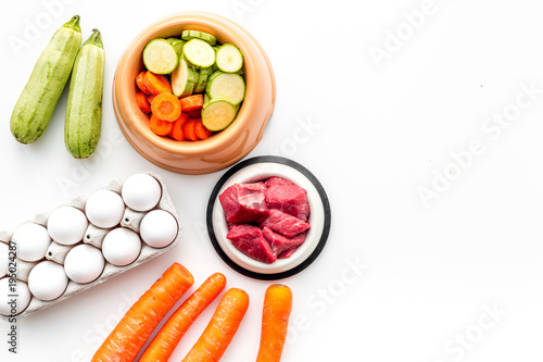 Ingredients on for pet food. Raw meat and vegetables on white backgroud top view copy space