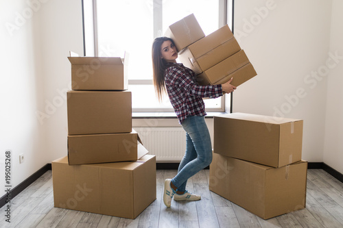 Young woman is transporting a filled cardboard in new apparment photo