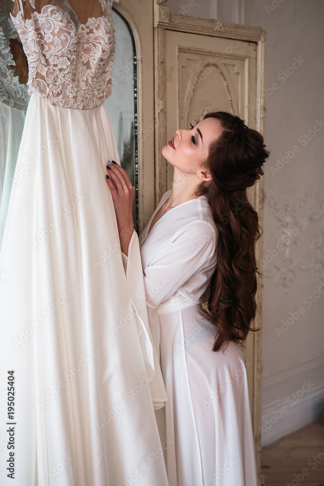 Beautiful bride in a white wedding peignoir in a morning. beauty portrait in interior Beautiful bride in a white wedding peignoir in a morning. beauty portrait in interior