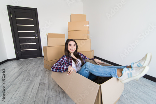 Cheerful woman sitting in a cardboard box white moving in new appartmant photo