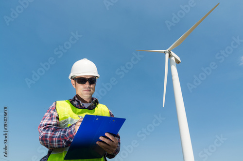 Electric Engineer writing report on Clipboard with Wind turbine power Generator