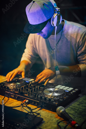 DJ with headphones playing mixing music at night party. Fun, youth, entertainment and fest concept.