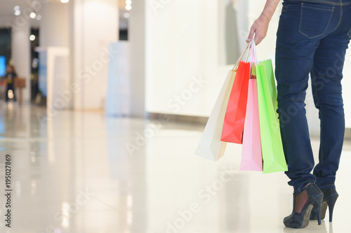 Close up of woman customer leg with colorful paper shopping bags