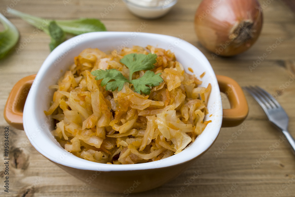 Appetizing stewed cabbage, sour cream, onion and lettuce leaves in the background. Appetizing stewed cabbage, sour cream, onion and lettuce leaves in the background.