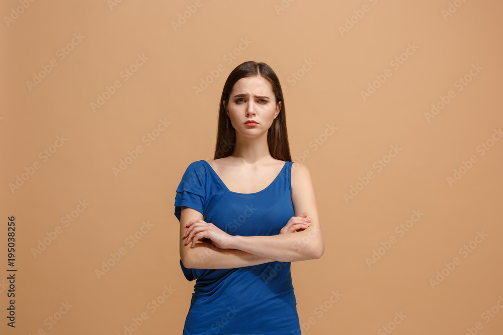 The sad woman standing and looking at camera against pastel background. The sad woman standing and looking at camera against pastel background.