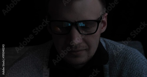 Man, face, with glasses, reflection, looking at graphics and work on the Internet, black background.
