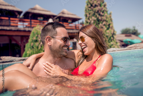 Young happy couple enjoying in swimming pool