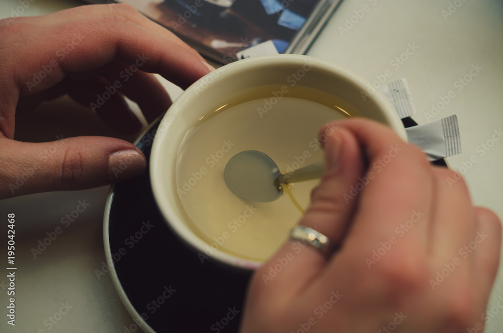 hand hold cup with green tea with teaspoon and magazine close up photo