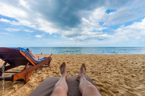 Men s legs on sunbed on the beach