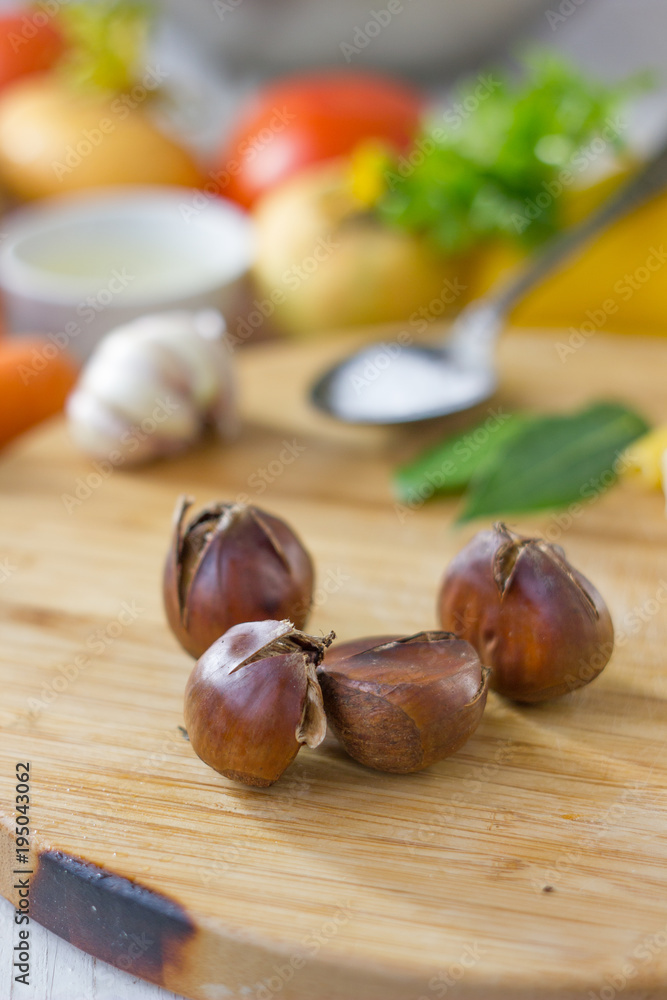 Roasted chestnuts on wooden board with vegetables. Roasted chestnuts on wooden board with vegetables.