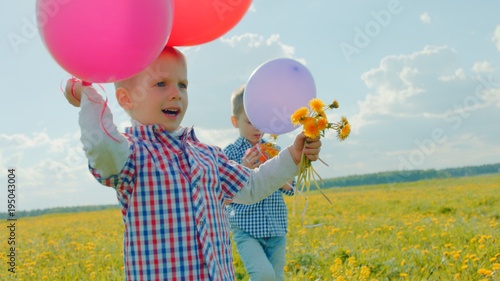 Happy little boys with balloons and flowers on summer holidays