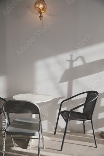 Wooden table and chairs with lamp on wall © Oran Tantapakul