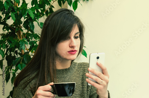Beautifur girl using smartphone and drinking coffee