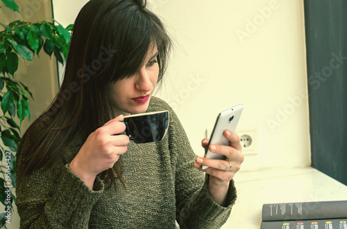 Beautifur girl using smartphone and drinking coffee