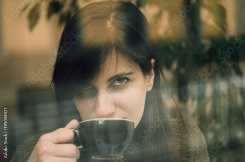 Young beautiful woman sitting in cafe, drinking coffee. Image toned