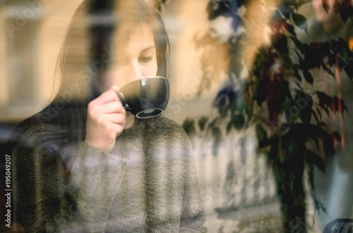 Young beautiful woman sitting in cafe, drinking coffee. Image toned