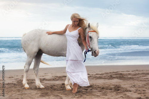 Beautiful young woman walking with horse at the beach, horseback © petunyia