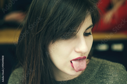 Emotional girl. Beautiful modern model shows tongue Positive woman hipster. Emotions on face.