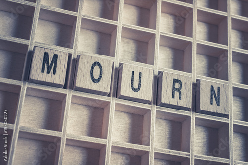 Closeup Of The Word Mourn Formed By Wooden Blocks On A Wooden Floor photo