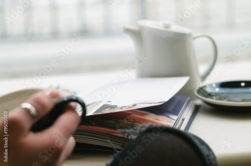 Young Woman Enjoying her coffee or tea in cafe, Looking Out the Window on streets of city .