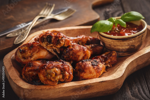 Oven baked chicken drumsticks on wooden tray.