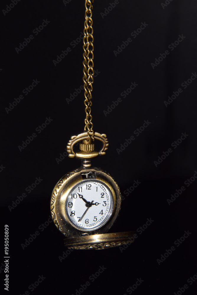 Ornamented Old Fashioned Pocket Watch Hanging by the Chain on Black Background Ornamented Old Fashioned Pocket Watch Hanging by the Chain on Black Background