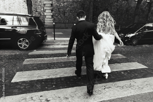 Look from behind at bride and groom crossing the street somewhere in Paris