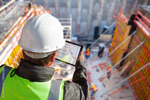 Fotobehang civil engineer or architect on construction site checking schedule with tablet c