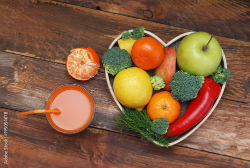 Fruits and Vegetables in Heart shaped Wooden Box. Broccoli, apples, Pepper, tangerine and glass of juice over Wooden Background. Banner. Health food Concept with copy space. photo